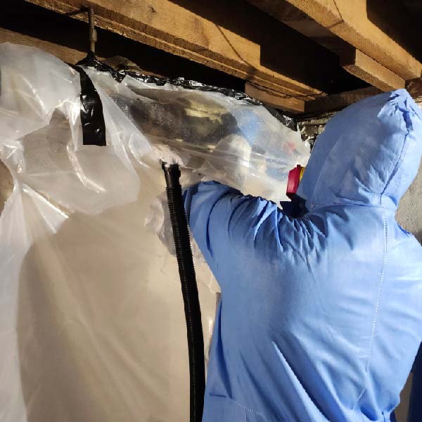 Certified asbestos abatement worker installing containment barrier